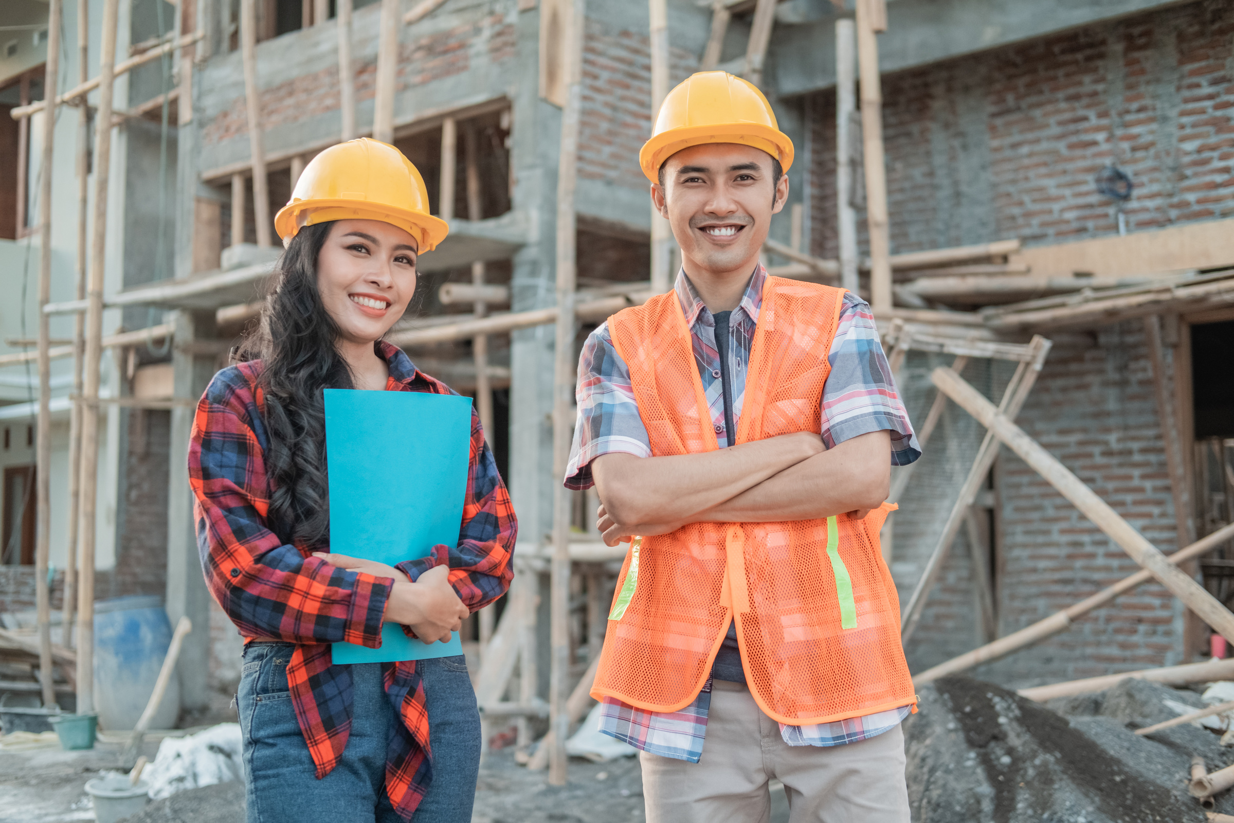 Asian Construction Workers Smiling Men and Women at the Camera Wearing Vests and Safety Helmets